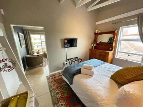a bedroom with a large bed and a bathroom at Calm Waters Guesthouse: Robberg Room in Plettenberg Bay