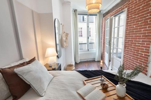 une chambre avec un lit et un mur de briques dans l'établissement Angers - 1 chambre et balcon aux Halles, à Paris