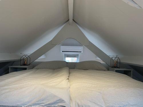 ein weißes Bett in einem Zimmer mit 2 Tischen in der Unterkunft Waltrilo in Waalre