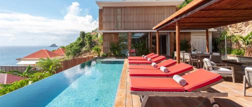 een rij rode ligstoelen naast een zwembad bij Luxury Vacation Villa 4 in Gustavia