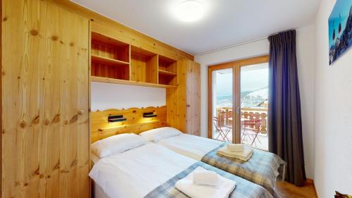een slaapkamer met een groot bed en een raam bij Pracondu 1 404 - OUTDOOR & FUN charming apartment in Nendaz