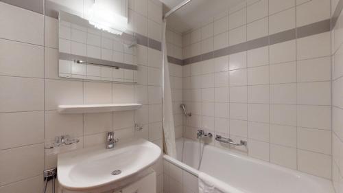 een witte badkamer met een wastafel en een bad bij Pracondu 1 404 - OUTDOOR & FUN charming apartment in Nendaz