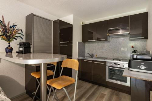 une cuisine avec des armoires noires, une table et des chaises dans l'établissement Appartment T2 à Lourdes, à Lourdes