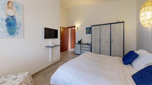 a bedroom with a white bed and a television at Poisson Rouge in Bonifacio
