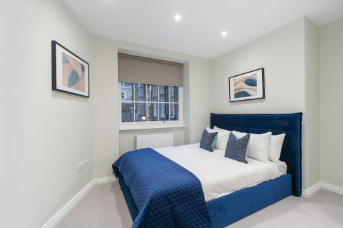 sypialnia z niebiesko-białym łóżkiem i oknem w obiekcie Urban Chic - Acre w Londynie