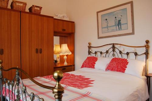 a bedroom with a bed with red pillows on it at Beach Vista Apartment One in Barmouth in Barmouth