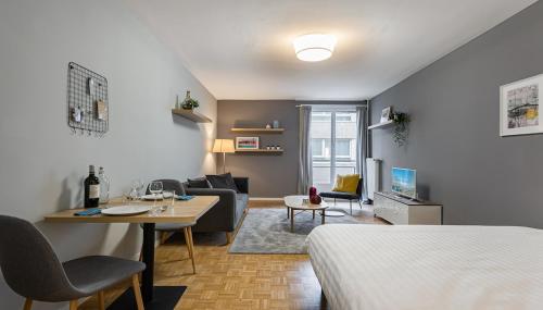 uma sala de estar com uma cama, um sofá e uma mesa em Richemont Residence by Homenhancement em Genebra