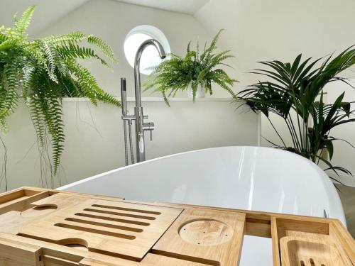 a white surfboard sitting on top of a table with plants at Meadow Guesthouse - Private Hot Tub in Rossett