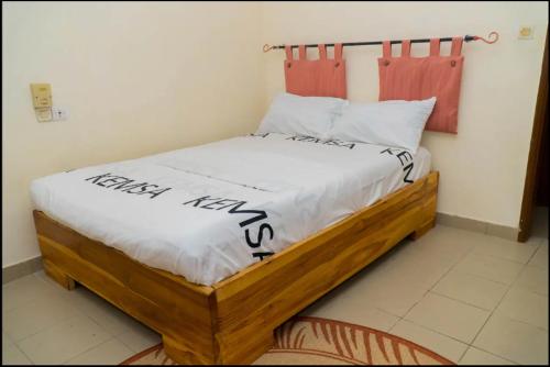 a bedroom with a wooden bed with a happy new year written on it at Maison d'hôte zouma in Ouéto