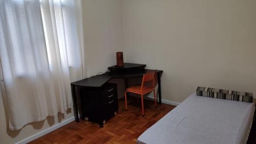 a bedroom with a desk with a chair and a bed at 2 quartos Icaraí in Niterói