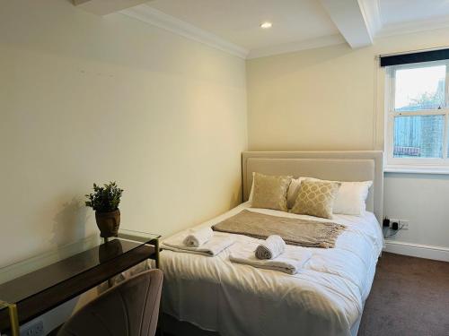a small bedroom with a bed and a desk at Wimbledon Elegance: 2-bedroom Retreat in London