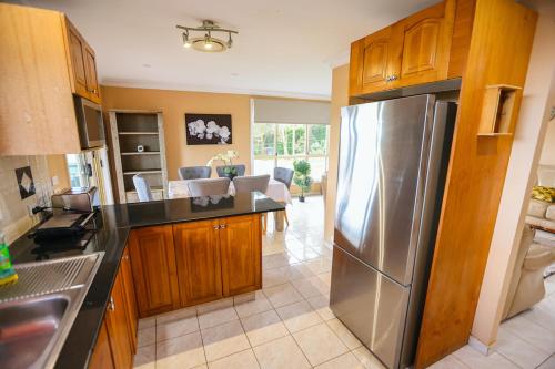 a kitchen with a stainless steel refrigerator and wooden cabinets at Entire House Beautiful Farm Stay 9 Bedrooms Sleeps 18 Enjoy Nature in Mangrove Mountain