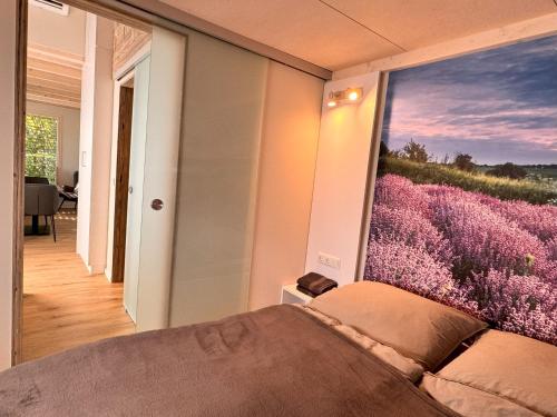 a bedroom with a large window with a purple flower mural at Tiny Haus Park Fritzlar in Fritzlar