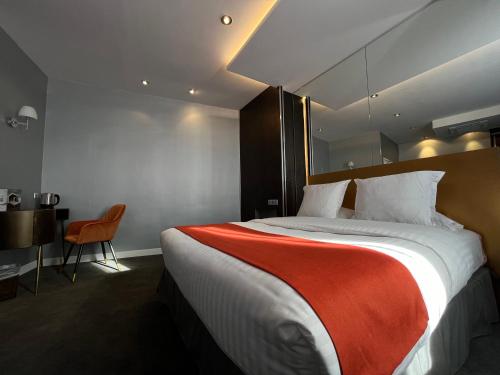 een hotelkamer met een groot bed en een stoel bij LOGIS Hôtel Borel in Duinkerke