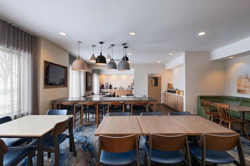 a dining room with tables and chairs and a kitchen at Fairfield Inn & Suites Kansas City Airport in Kansas City
