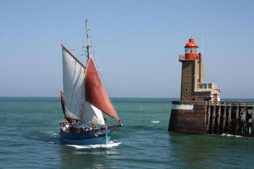 a sail boat in the water near a lighthouse at Chez Catherine - Chaumière Normande in Theuville-aux-Maillots