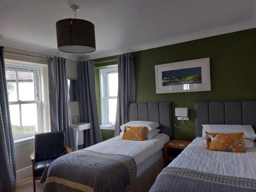 two beds in a room with green walls and windows at Seaview Guesthouse in Mallaig
