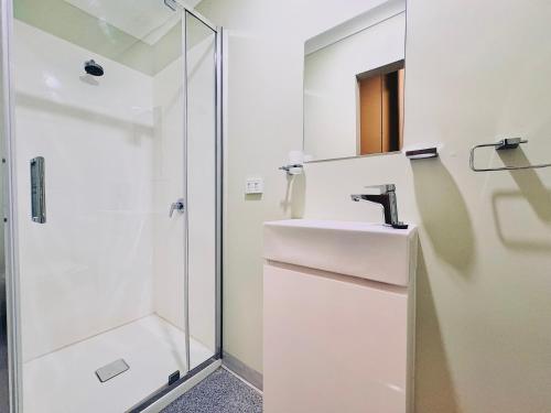 a white bathroom with a sink and a shower at Exchange Hotel Greenbushes in Greenbushes