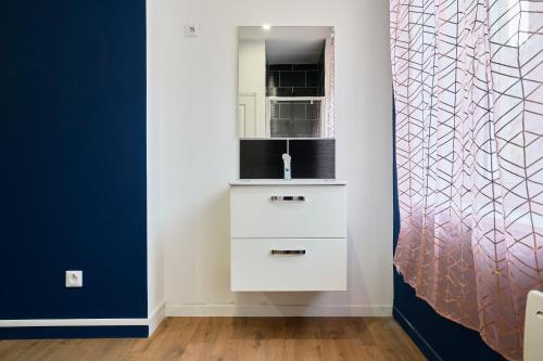 Cette chambre comprend une commode blanche et un miroir. dans l'établissement NG Prestige - Lille l Roubaix Trichon - Balnéo - Babyfoot, à Roubaix