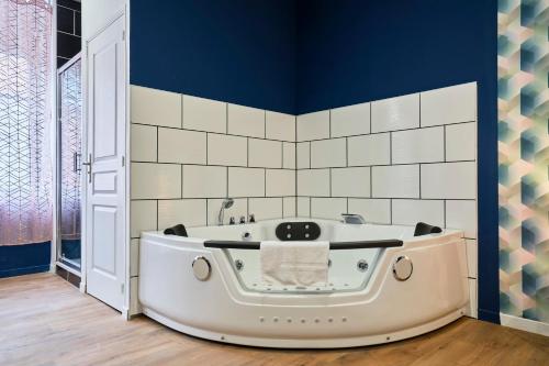 La salle de bains est pourvue d'une baignoire et de murs bleus. dans l'établissement NG Prestige - Lille l Roubaix Trichon - Balnéo - Babyfoot, à Roubaix