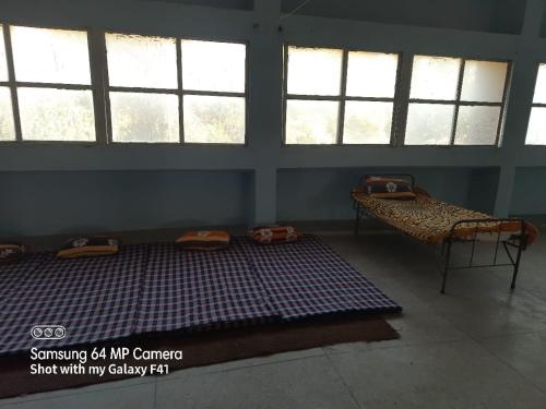 a room with two beds in a room with windows at Shubhi Rest House and Restaurant in Sehore