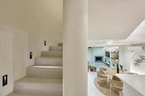 a white staircase in a living room with a table and chairs at The Sand Villa in Agios Nikolaos