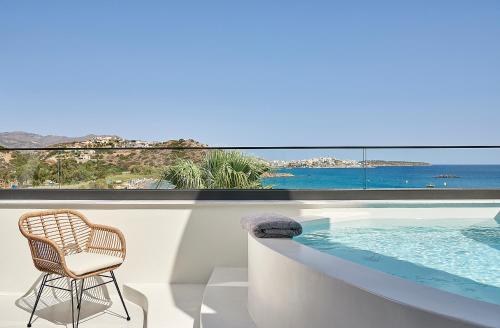 a wicker chair sitting next to a swimming pool at The Sand Villa in Agios Nikolaos