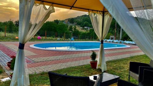 uma piscina com um guarda-sol, uma mesa e cadeiras em Agriturismo Tre Elle em Acri
