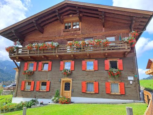 a wooden house with red shutters and flowers on it at Haus Peintner in Tannheim
