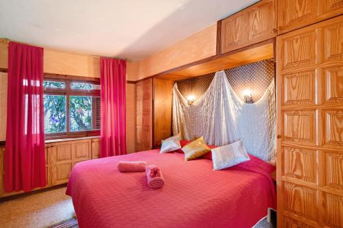Un dormitorio con una gran cama roja con cortinas rosas en A Paradise for your Soul en La Matanza de Acentejo