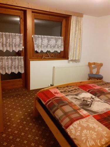 a bedroom with a bed and a chair and windows at Haus Peintner in Tannheim