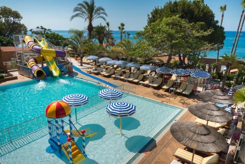 a pool with a water slide and chairs and umbrellas at Amathus Beach Hotel Limassol in Limassol