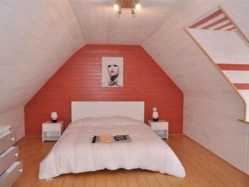 - une chambre avec un grand lit et un mur rouge dans l'établissement Maison Pleumeur-Bodou, 4 pièces, 6 personnes - FR-1-368-13, à Pleumeur-Bodou