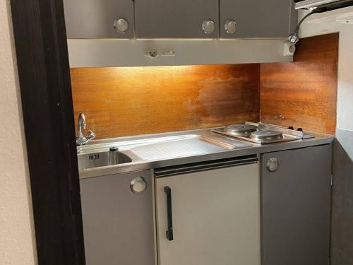 une petite cuisine avec un évier et une cuisinière dans l'établissement Appartement 6 pers. face aux pistes, balcon sud, TV, cuisine équipée, ski-in/ski-out, La Mongie - FR-1-404-78, à La Mongie