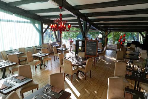 a restaurant with tables and chairs and a chandelier at Hotel du Lac Foix in Foix