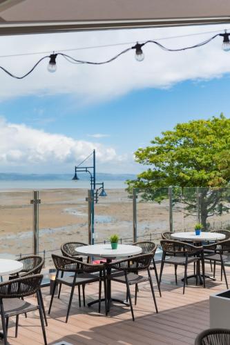 a patio with tables and chairs and the beach at Oyster House in The Mumbles