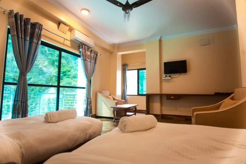 Shrestha Hotel Hotspring PVT.LTD في Beni: غرفة فندقية بسريرين وتلفزيون