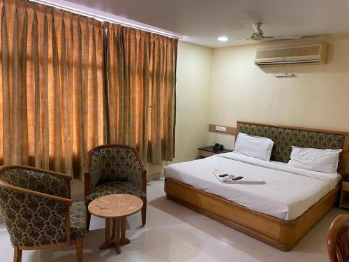 Habitación de hotel con cama y silla en NakshaTree Hotels, Maruthi Residency -Mogappair, en Chennai