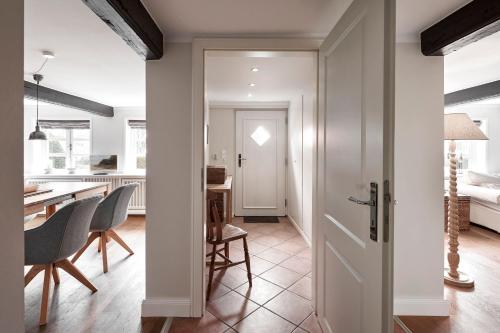 - une cuisine et une salle à manger avec des murs blancs et une porte dans l'établissement Apartment Koob, à Wyk auf Föhr