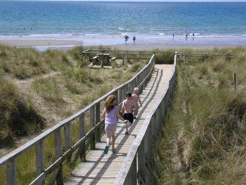 a couple of people walking down a boardwalk to the beach at Beach Vista Apartment Three in Barmouth in Barmouth