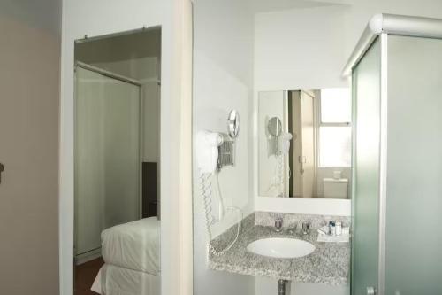 a bathroom with a sink and a mirror and a bed at Max Savassi Apart Service in Belo Horizonte