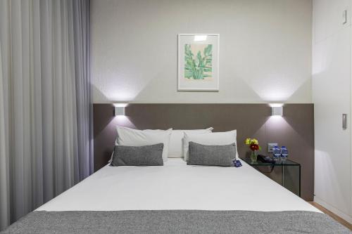 1 dormitorio con 1 cama grande con sábanas y almohadas blancas en Max Savassi Apart Service en Belo Horizonte