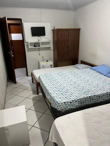 a bedroom with two beds and a tv on the wall at Pousada Água Viva in Maceió