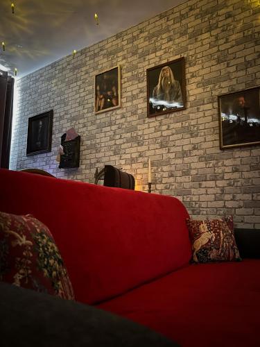 - un canapé rouge dans une pièce dotée d'un mur en briques dans l'établissement Le Repaire des Sorciers, à Morlaix