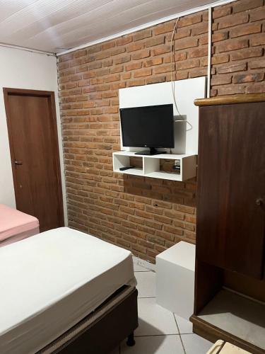 um quarto com uma cama e uma televisão numa parede de tijolos em Pousada Água Viva em Maceió