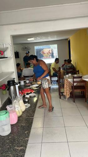 Pousada Água Viva في ماسيو: رجل واقف في مطبخ يحضر الطعام