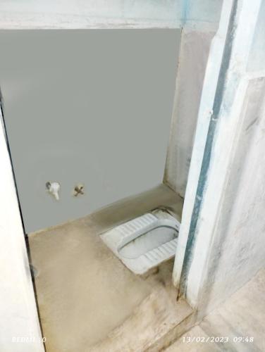 a bathroom with a toilet in the corner of a room at Shubhi Rest House and Restaurant in Sehore