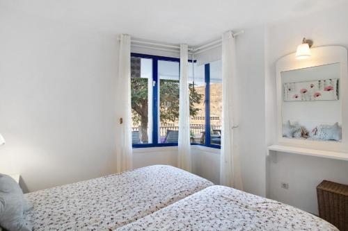 a white bedroom with a bed and a window at Views of Sunsets in Taurito