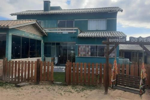 una casa azul con una valla de madera delante de ella en casa maravilhosa a Beira-Mar da Salinas, en Cidreira