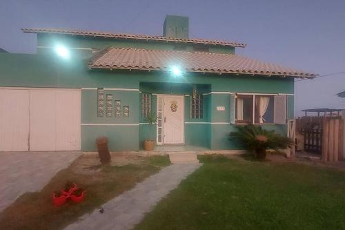 una casa verde con una puerta blanca y luces en casa maravilhosa a Beira-Mar da Salinas, en Cidreira